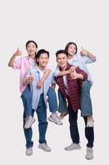 Obraz premium Two young couples giving piggyback rides and thumbs up symbolizing friendship and support