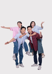 Obraz premium Four joyful friends two men giving piggyback rides to two women all smiling and cheerful