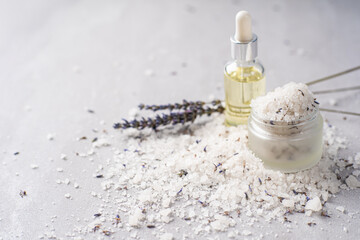 Lavender bath products and accessories arranged on a light background with scattered salt and a...