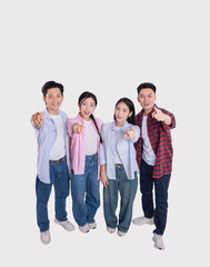 Four diverse young adults pointing directly forward smiling and dressed in casual attire on white...