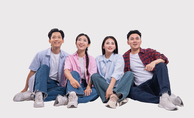 Four smiling individuals sit casually on the floor looking upwards with curiosity and wonder