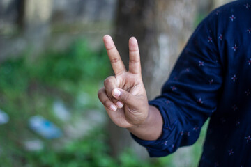 A man pointing two fingers of his hand forward and green background