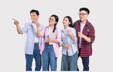 Four young adults likely students are standing together pointing in the same direction in a studio...