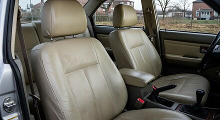 Car Interior Aesthetics: Beige Leather Front Seats Showing Signs of Use and Minor Dirt, Indicating the Need for Automotive Cleaning and Detailing

