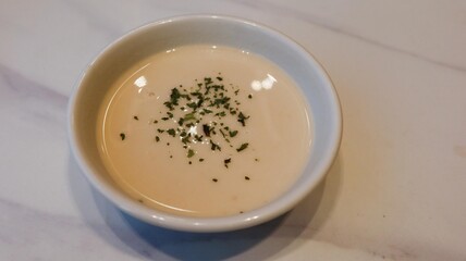 close up of cream chowder soup with herbs as topping on the marbled table