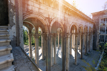Abandoned neoclassical colonnade with Corinthian columns and sunlight rays. Historical architecture, tourism, and vintage design concepts.