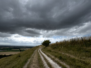 Fototapeta premium A peaceful rural scene showing a hillside path under a cloudy sky, with open views across the countryside.