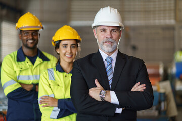 A foreman and worker are standing in a factory, looking standing pose. They wear a yellow and white...