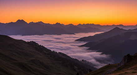 Obraz premium Golden-hour light illuminates layered mountain ridges above a thick blanket of fog, creating a peaceful and majestic scene.