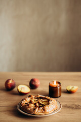 Appetizing homemade peach galette on wooden kitchen table.