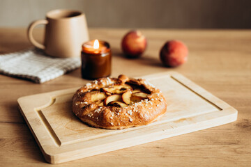 Appetizing homemade peach galette on wooden kitchen table.