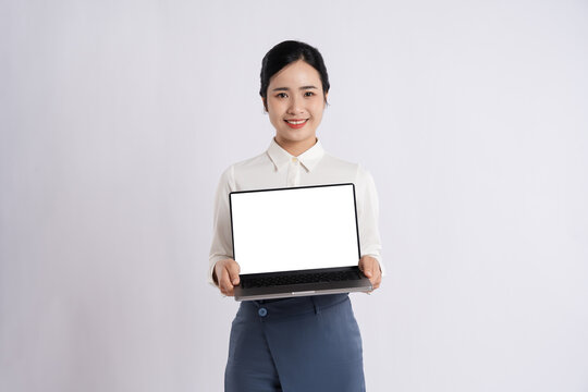 Smiling woman in business attire holding a laptop with a blank screen ready for customization