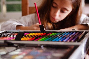A young girl painting with colorful pencils.