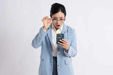 Businesswoman looking shocked at phone holding eyeglasses in hand Pale blue business suit