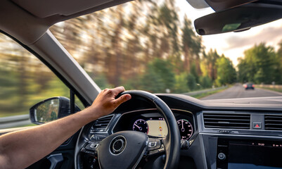 Driver hand on wheel. Motion blur trees. Fast summer road trip.