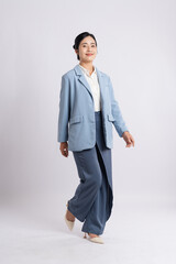 Stylish woman in a light blue blazer dark trousers and cream-colored shoes confidently strides