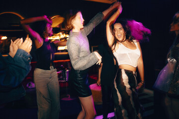 Friends dancing joyfully together at a nightclub during an evening celebration