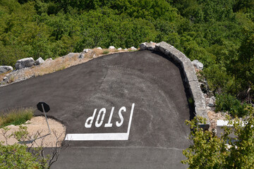A high-angle view shows an asphalt road curving sharply with an upside-down 