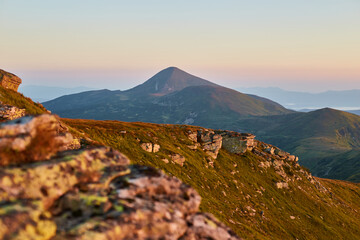 Mountain landscape at sunrise showcasing a prominent peak and rugged terrain in serene wilderness....