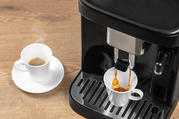 A modern coffee machine brews fresh espresso into a white cup while another steaming cup sits ready...