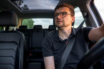 Focused man driving car. Evening ride. Driver looking aside.
