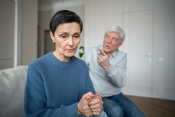 Detached inward focused woman fearing husband shouts and gestures in background, emotional...