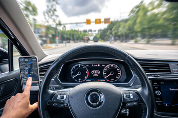 Driver at steering wheel. Car dashboard. GPS on smartphone.
