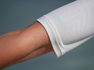 Close-up of a hand wearing a white protective sleeve with UPF 50 for high ultraviolet protection