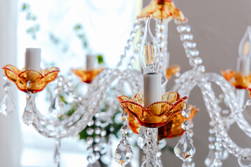 Colorful chandelier with floral design and sparkling crystals illuminated in a bright indoor setting