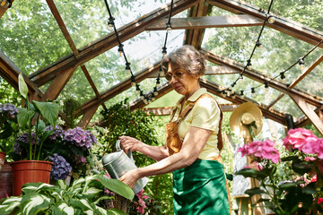 Senior woman nurturing vibrant flowers in a tranquil garden setting surrounded by greenery