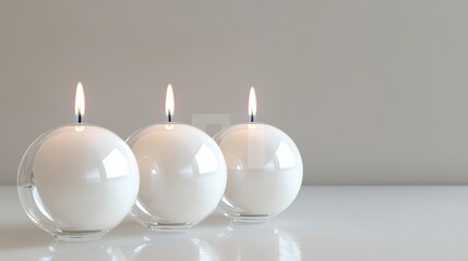 Three white candles in clear glass globes