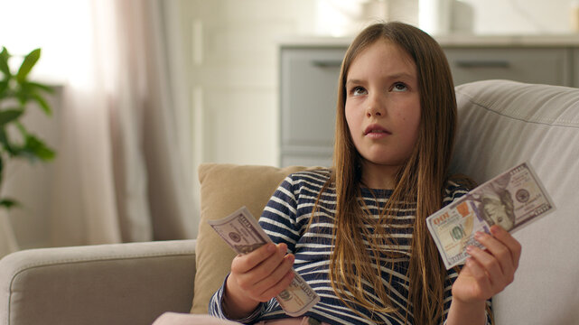 Little European girl counting dollars bills money finance child kid cash currency exchange hundred savings wealth budget banknotes daughter female bank buying economic earnings income payment salary