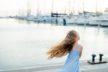 Portrait of a little girl on the seashore in a French town near a yacht marina.