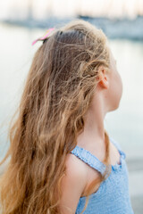 Portrait of a little girl on the seashore in a French town near a yacht marina.
