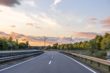 Road and wind turbines at sunset. Energy of motion. Modern nature