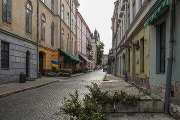 Empty cobblestone street in historic European city with colorful old buildings, Ukrainian flag, and...