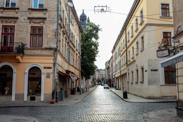Historic European street view with cobblestone road, old buildings with arched windows and signs,...