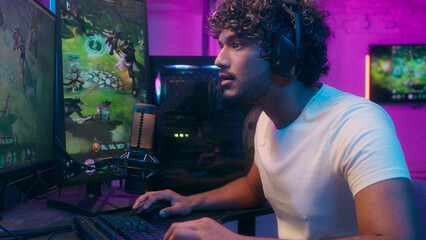 Focused Arabian Indian Latino man talking speaking playing video game gamer computer tech happy...