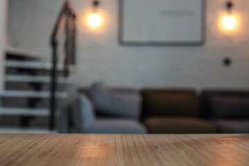 Modern loft interior with a close-up view of a wooden tabletop in focus. In the blurred background:...