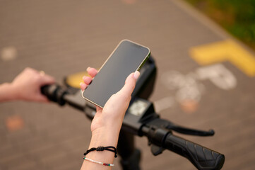 woman using smartphone while riding electric scooter on urban path in daylight. lifestyle technology scene highlighting modern mobility and connectivity outdoors