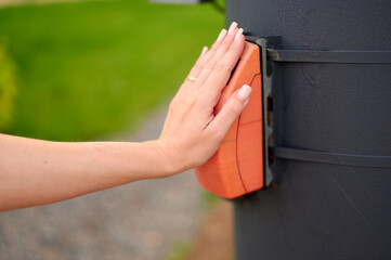 hand pressing wooden button on black pole in outdoor setting. focus on tactile interaction and fit...