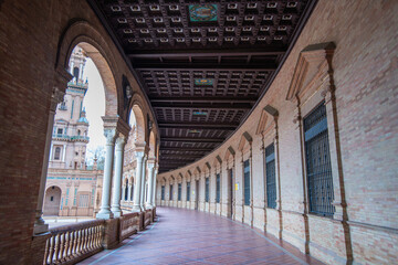 Sevilla Plaza de Espana in Spain features an ornate arcade with a historic tower view, built in...