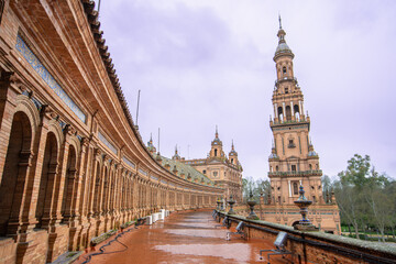 Obraz premium Sevilla Plaza de Espana in Spain shows a fountain under a rainy spring dusk sky, with ornate architecture and colorful tiles enhancing the serene scene.