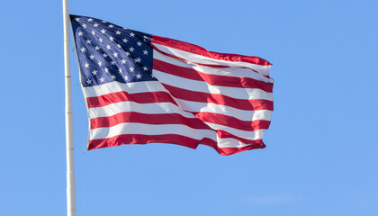 american flag of united states america usa blowing in the breeze flying high on flag pole patriotic...