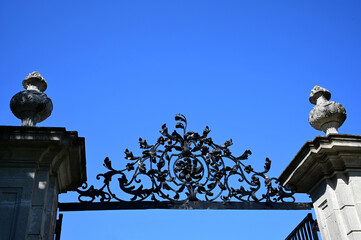 decorative isolated wrought iron gate top portion between stone pillars in the city of Eger, Hungary. blue sky background. beautifully detailed metal work. architecture, travel and tourism concept