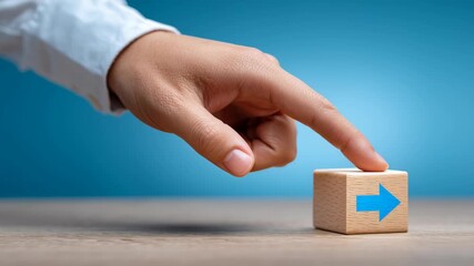 Finger hand pointing pressing wooden block with blue arrow symbol on wooden surface showing direction progress guidance concept