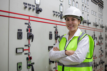 Power station control room engineer smiling confidently with arms crossed wearing safety helmet and...