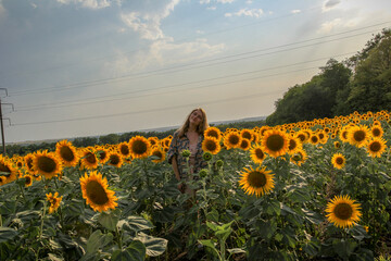young blonde woman standing in sunflower field, full face, distant view, waist-length portrait, large yellow flowers, posing, smiling, summer, model, 