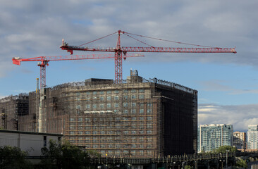 scaffolding covering over building facade during crane construction built infrastructure industrial...