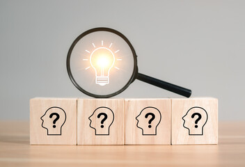 Innovation and Problem Solving Concept. Magnifying glass focuses on light bulb icon above wooden...